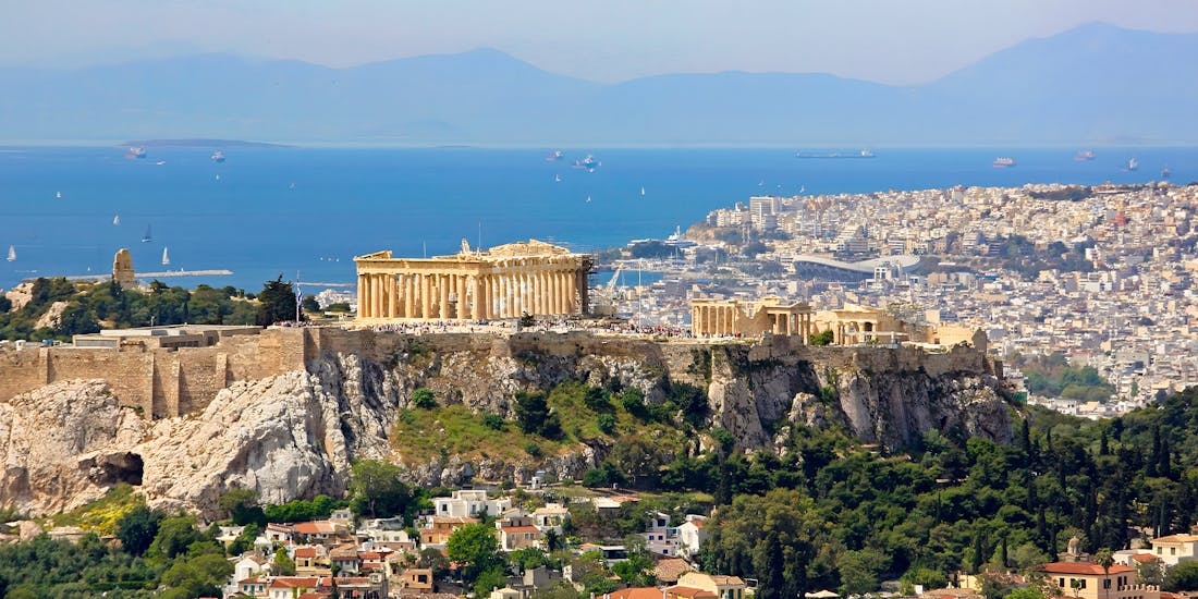 Acropolis on a hill in Athens with ancient ruins and Parthenon visible.