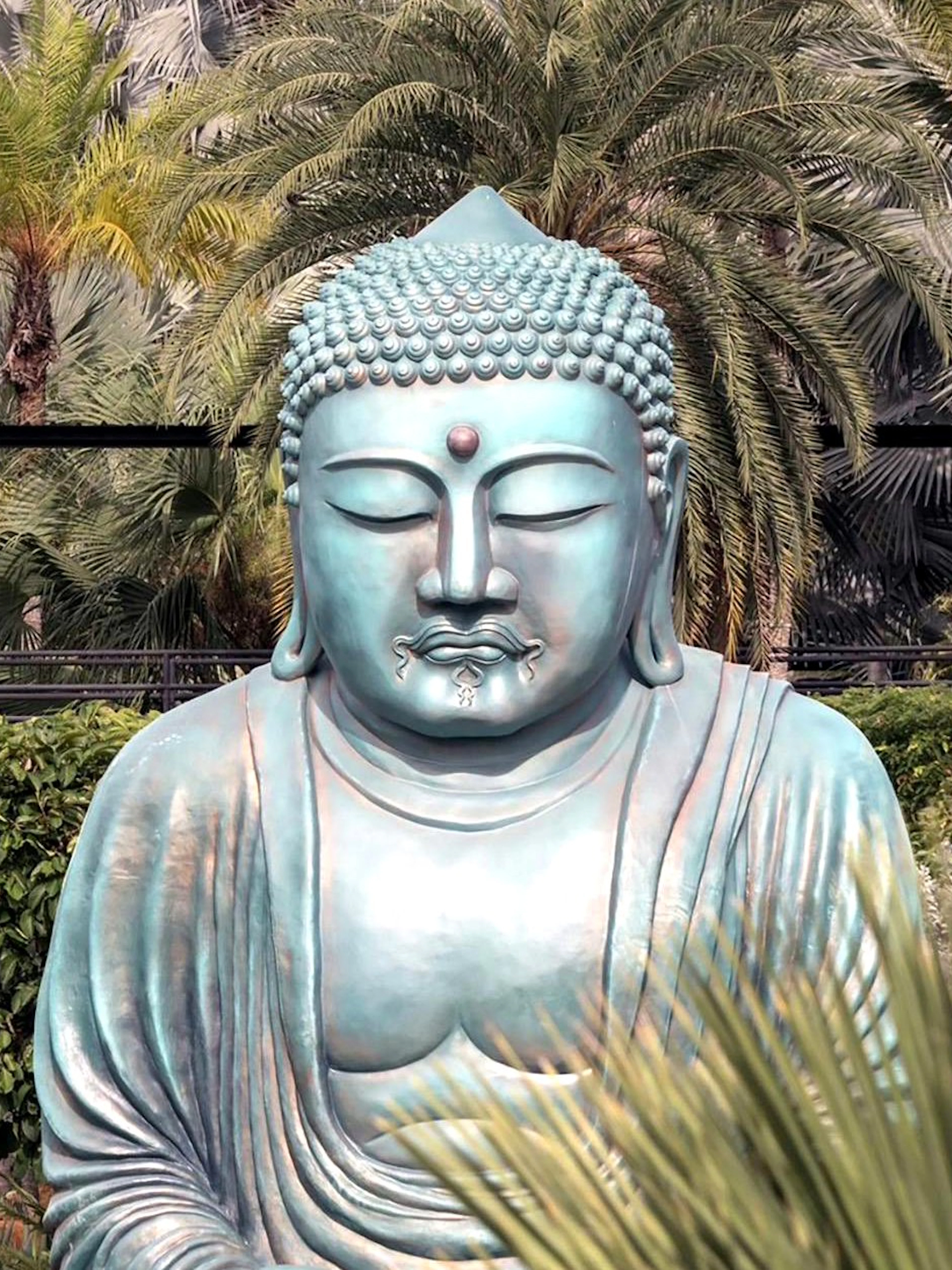 Buddha statue surrounded by tropical plants at Nong Nooch Tropical Garden, Thailand.