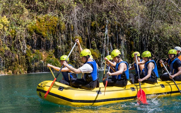 Rafters paddling on the Cetina River in a yellow inflatable boat.