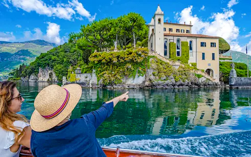 Tourists on a boat admire Villa del Balbianello on Lake Como, Italy.