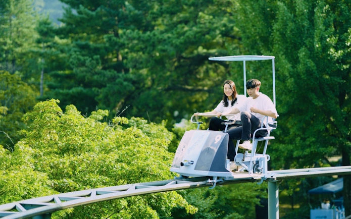 Couple enjoying rail bike ride through lush greenery on Nami Island day trip from Seoul.