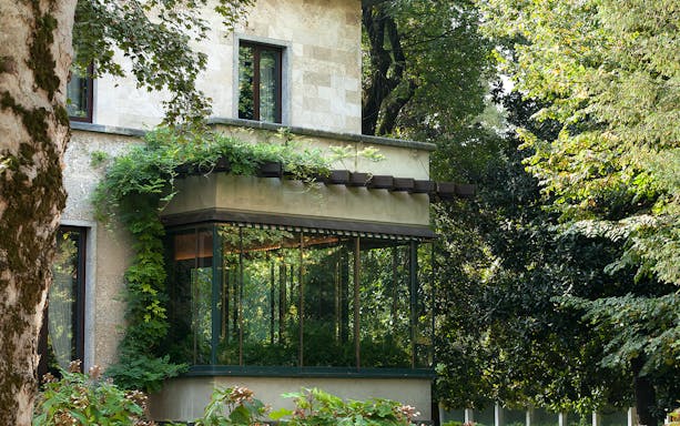 House Museum Card Milan, exterior view with greenery and large windows.