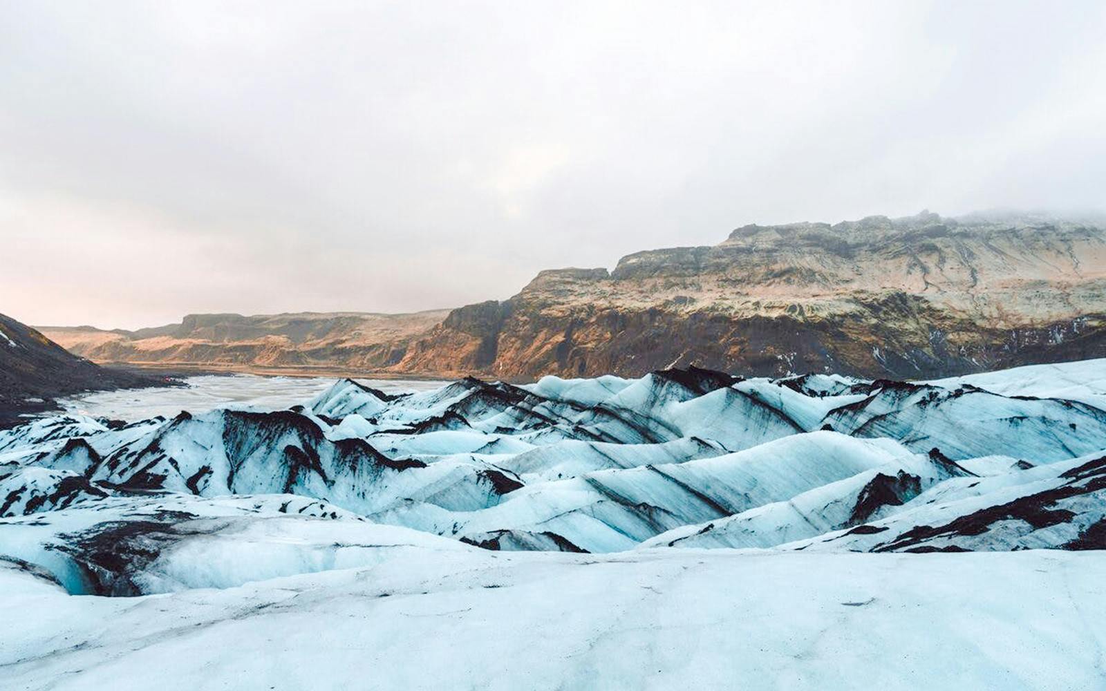 Sólheimajökull glacier with ice formations and distant rocky mountains in Iceland.