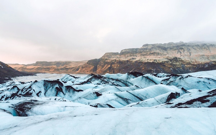 Sólheimajökull glacier with ice formations and distant rocky mountains in Iceland.