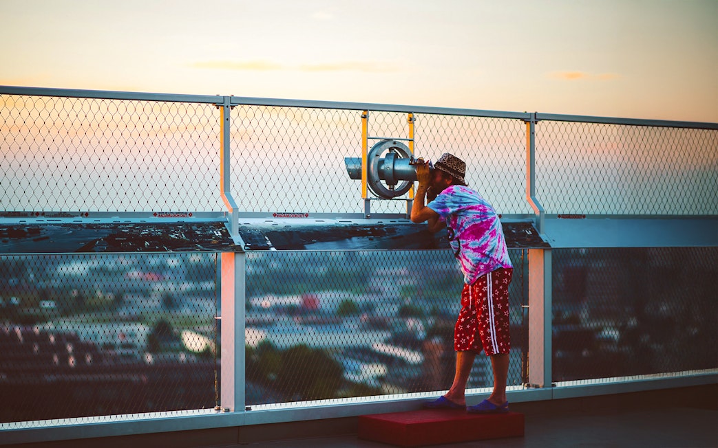 Person using a telescope at ADAM Lookout deck in Amsterdam.