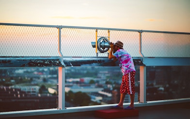 Person using a telescope at ADAM Lookout deck in Amsterdam.