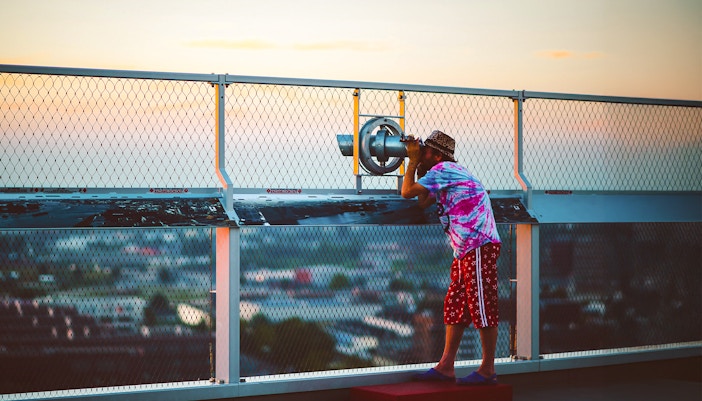 Person using a telescope at ADAM Lookout deck in Amsterdam.