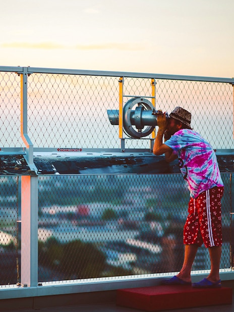 Person using a telescope at ADAM Lookout deck in Amsterdam.