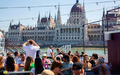 Guests on Budapest Danube River cruise with view of Hungarian Parliament Building.