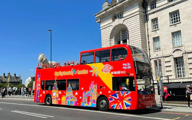 Open-top red double-decker bus on London street, part of Thames River Hop-On Hop-Off Cruise Tour.