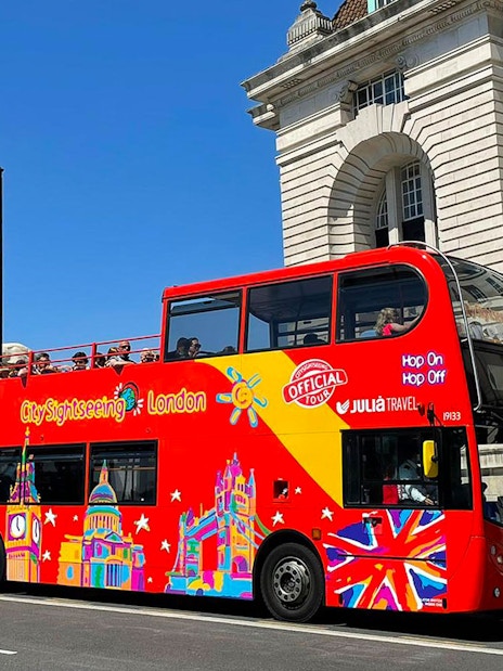 Open-top red double-decker bus on London street, part of Thames River Hop-On Hop-Off Cruise Tour.