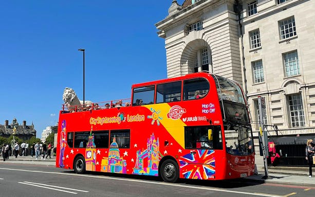 Open-top red double-decker bus on London street, part of Thames River Hop-On Hop-Off Cruise Tour.