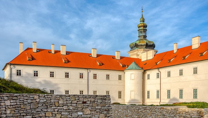 Jesuit College in Kutna Hora with red roof and stone wall in foreground.