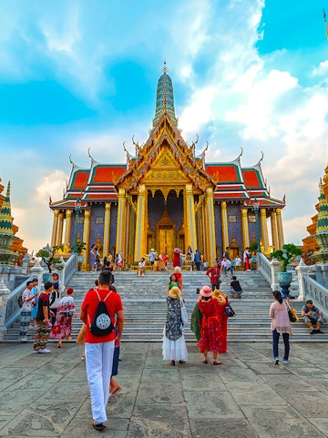 Visitors exploring the ornate entrance of the Grand Palace in Bangkok, Thailand.