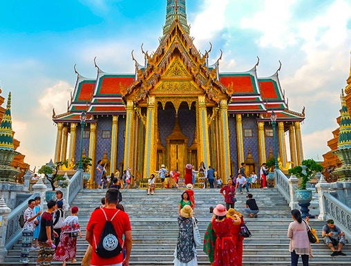 Visitors exploring the ornate entrance of the Grand Palace in Bangkok, Thailand.