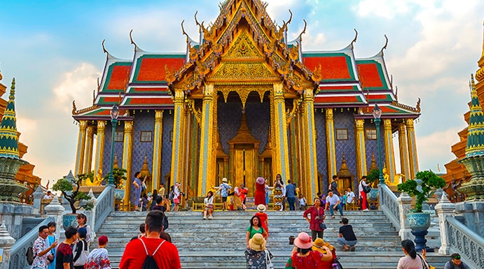 Visitors exploring the ornate entrance of the Grand Palace in Bangkok, Thailand.