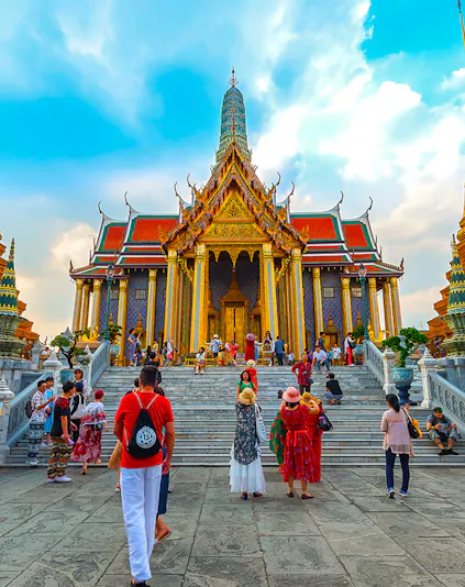 Visitors exploring the ornate entrance of the Grand Palace in Bangkok, Thailand.