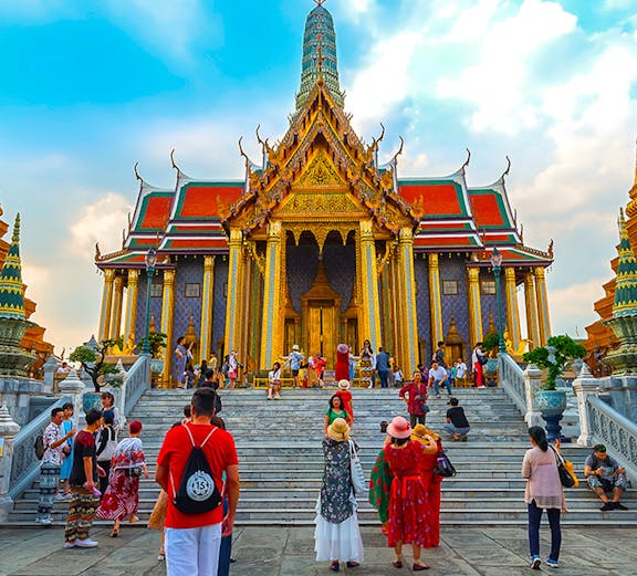 Visitors exploring the ornate entrance of the Grand Palace in Bangkok, Thailand.