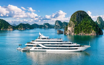 Luxury cruise ship in Ha Long Bay with limestone islands in the background.