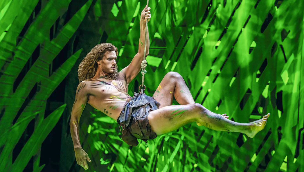 Performer swinging on vine in Disney's Tarzan stage show.