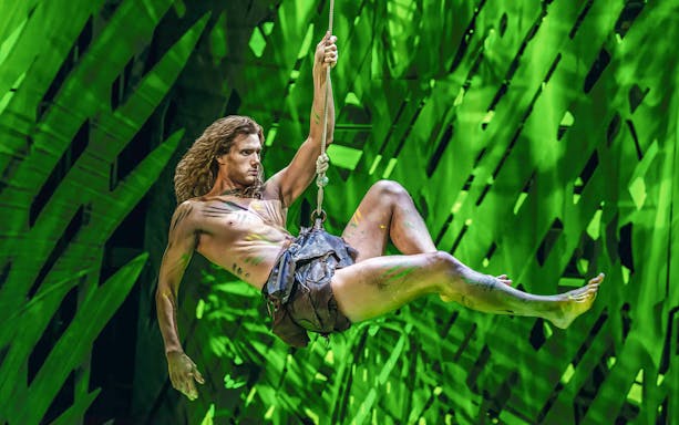 Performer swinging on vine in Disney's Tarzan stage show.