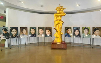 Golden statue and portraits in Hanoi museum exhibit.