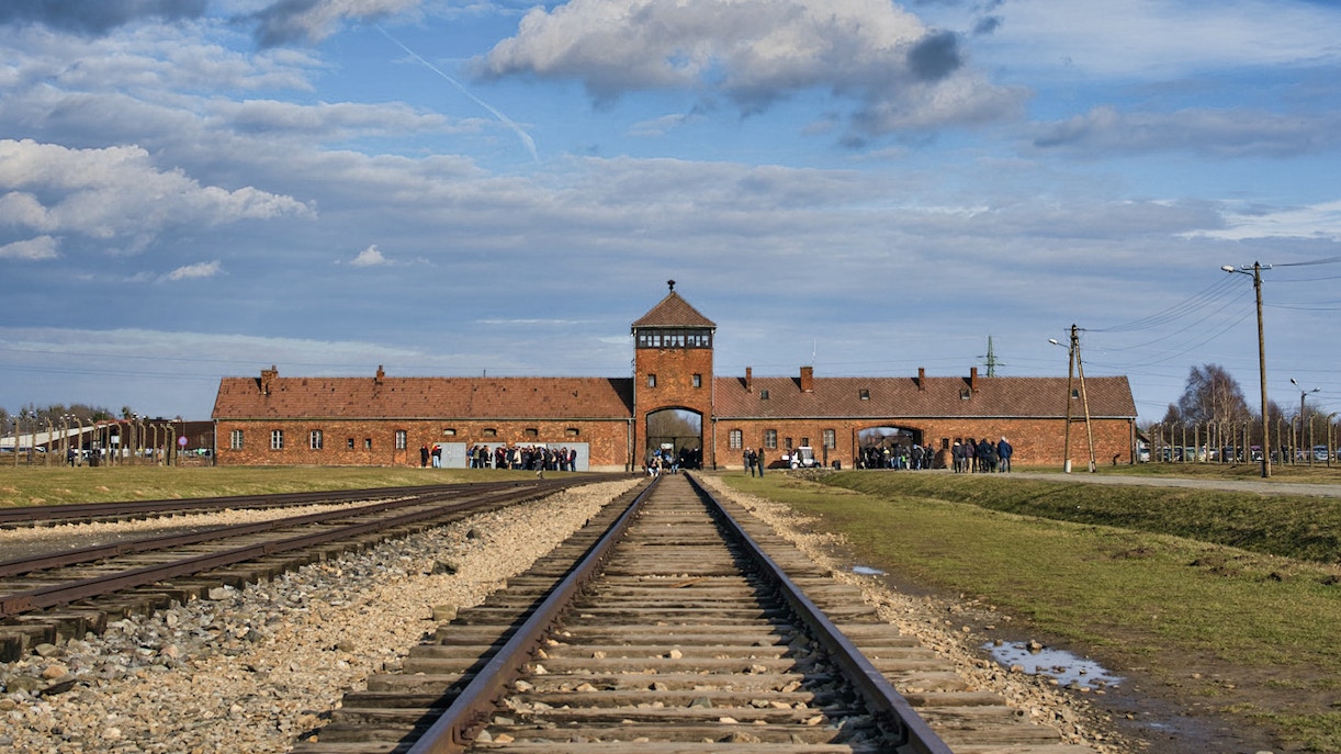 Auschwitz-Birkenau entrance gate with railway tracks leading into the concentration camp.