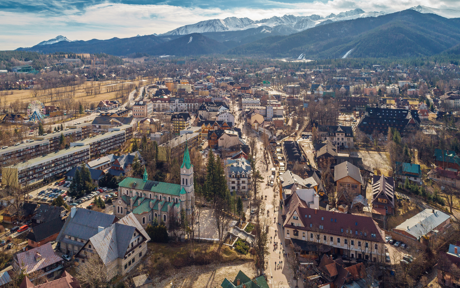 Aerial view of Zakopane with Tatra Mountains in the background, showcasing the town's architecture and landscape.