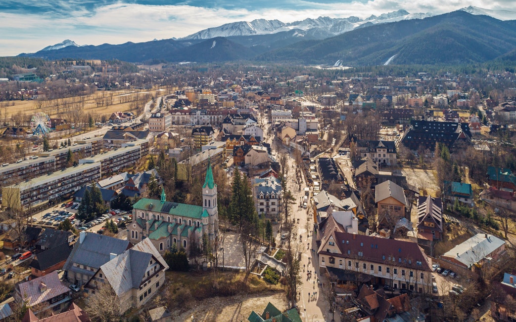 Aerial view of Zakopane with Tatra Mountains in the background, showcasing the town's architecture and landscape.
