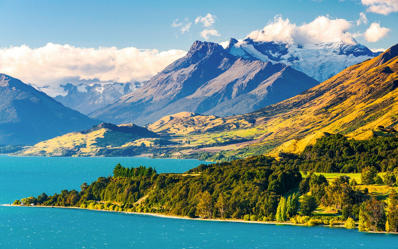 Mount Earnslaw with lush green hills and blue lake in New Zealand.