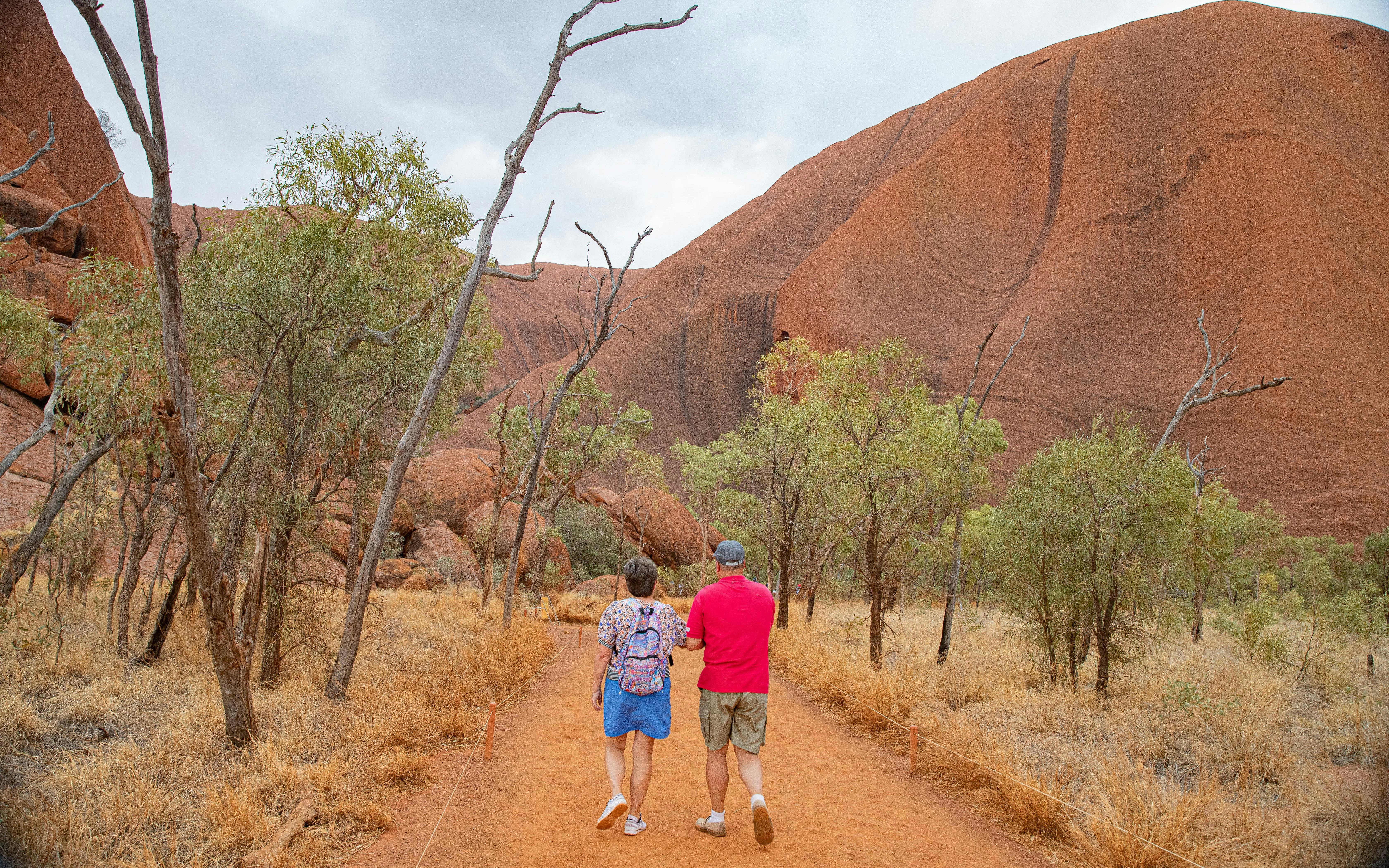 Visitors walking towards Uluru on a guided tour from Alice Springs.