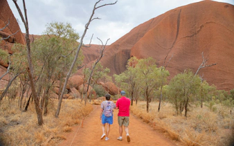Visitors walking towards Uluru on a guided tour from Alice Springs.