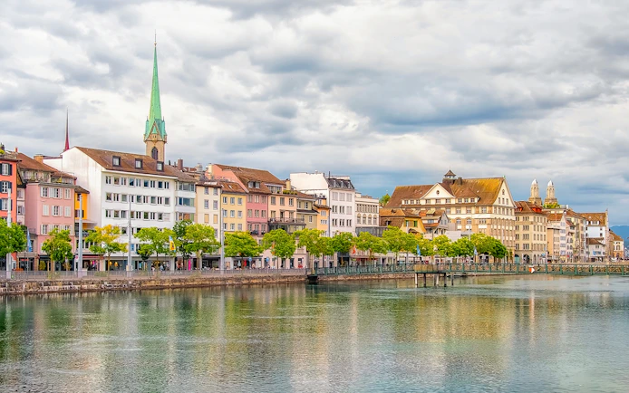 Historic buildings along the Limmat River in Zurich, featuring the Fraumünster Church spire.