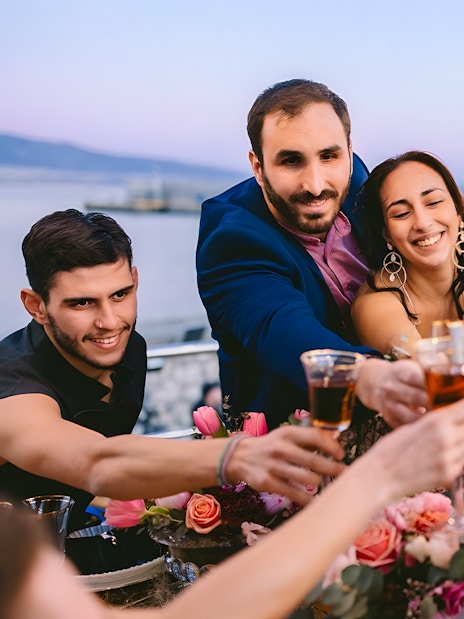 Guests toasting with drinks on Athens Riviera cruise with coastal views.