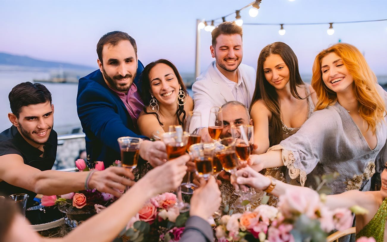 Guests toasting with drinks on Athens Riviera cruise with coastal views.