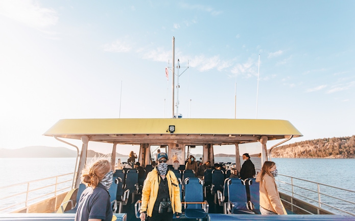 Covered boat with passengers on a half-day whale watching tour, scenic coastal view.