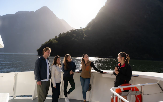 Group enjoying Milford Sound Extended Cruise with guide against mountain backdrop.