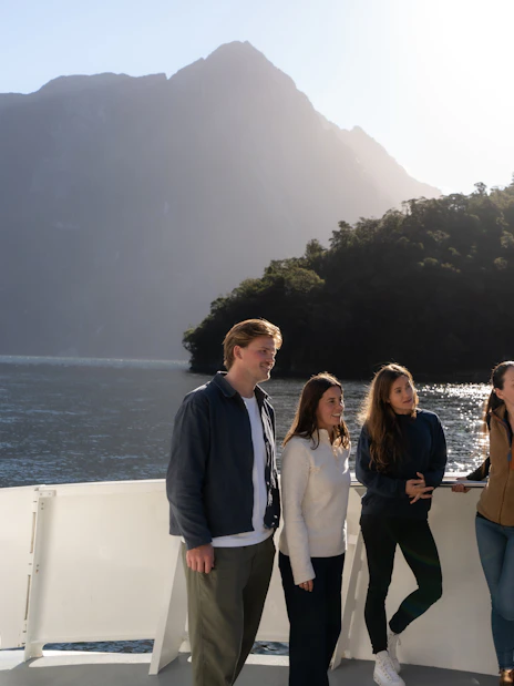 Group enjoying Milford Sound Extended Cruise with guide against mountain backdrop.