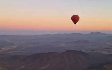 Hot air balloon over Marrakesh landscape at sunrise.