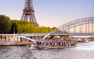 Seine River cruise boat near Eiffel Tower at sunset, Paris.