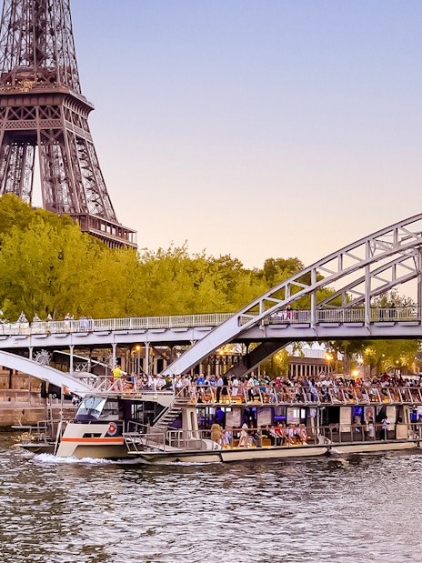 Seine River cruise boat near Eiffel Tower at sunset, Paris.