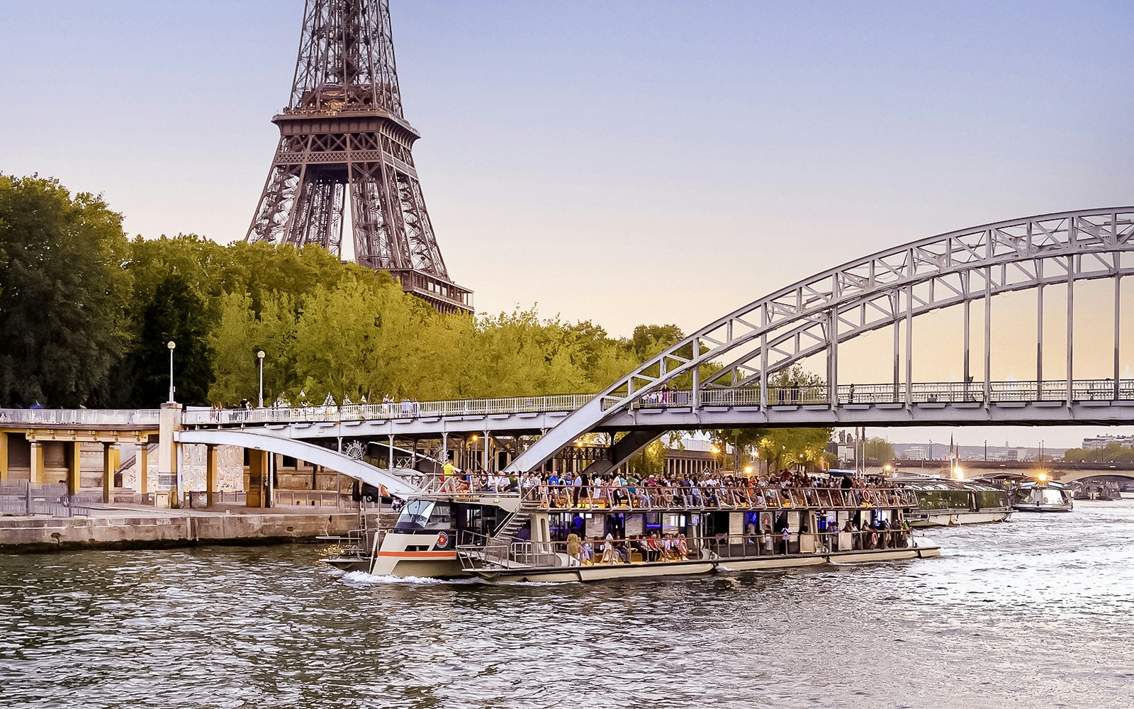 Seine River cruise boat near Eiffel Tower at sunset, Paris.