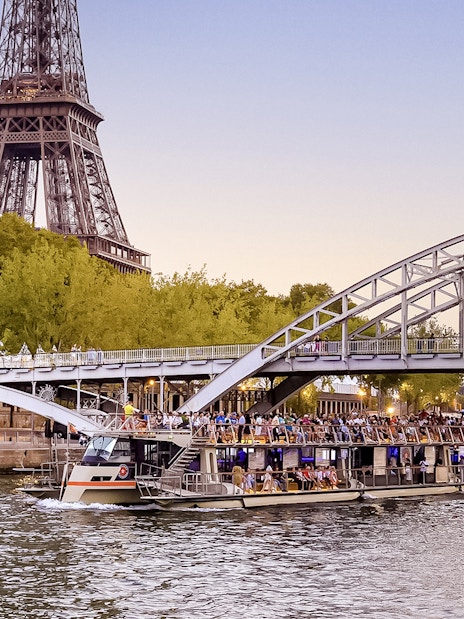 Seine River cruise boat near Eiffel Tower at sunset, Paris.