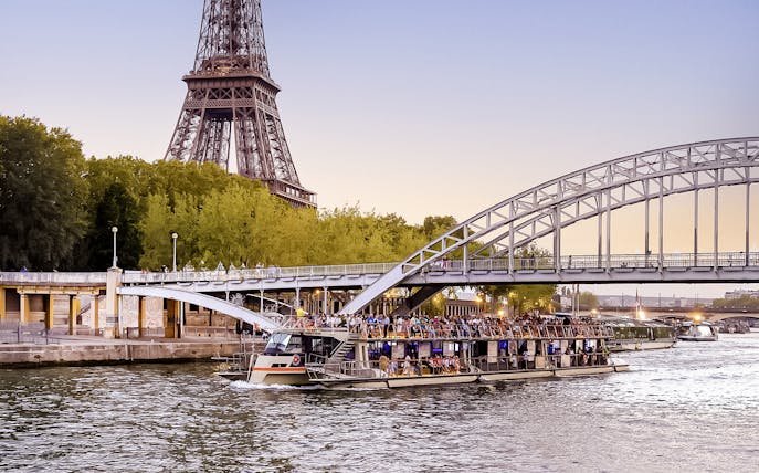 Seine River cruise boat near Eiffel Tower at sunset, Paris.