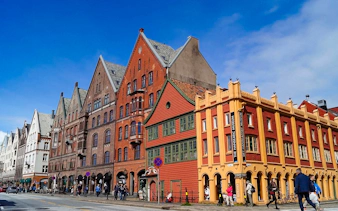 Bryggen Hanseatic Wharf historic buildings in Bergen, Norway, with people walking nearby.