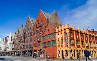 Bryggen Hanseatic Wharf historic buildings in Bergen, Norway, with people walking nearby.