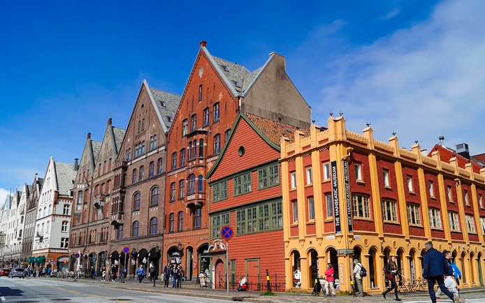 Bryggen Hanseatic Wharf historic buildings in Bergen, Norway, with people walking nearby.