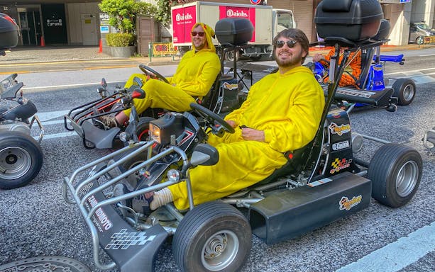 Go-kart riders in yellow costumes on Tokyo street during Asakusa photoshoot experience.