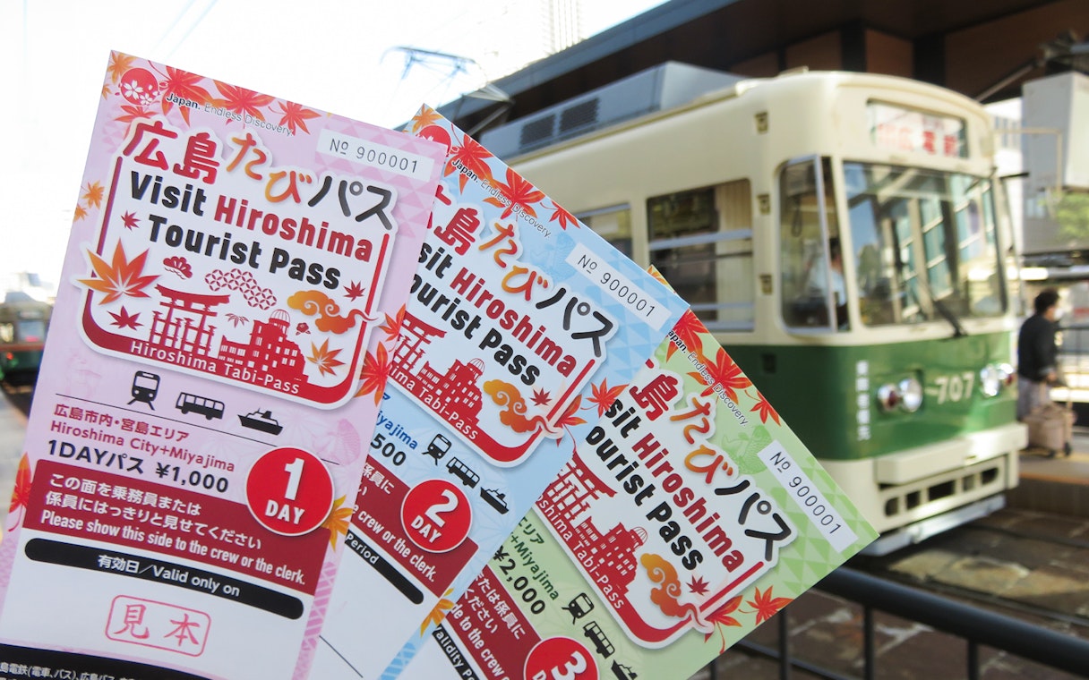 Hiroshima Tourist Passes held in front of a tram in Hiroshima, Japan.