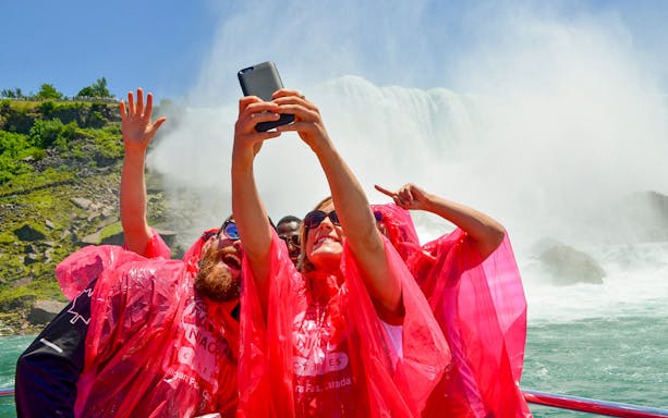 Tourists taking selfies on a boat ride at Niagara Falls.